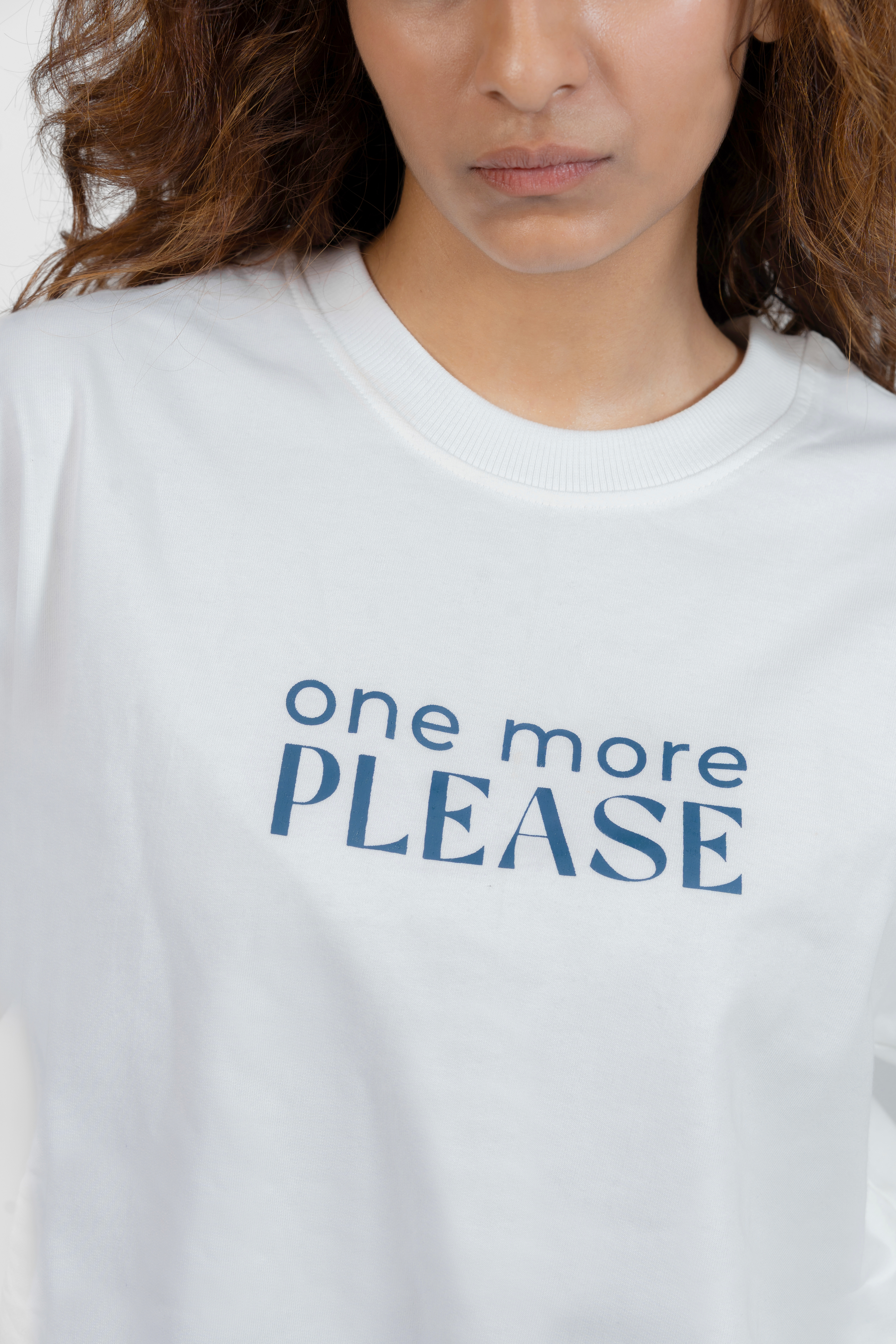 White t-shirt with blue text 'one more PLEASE' worn by a person.