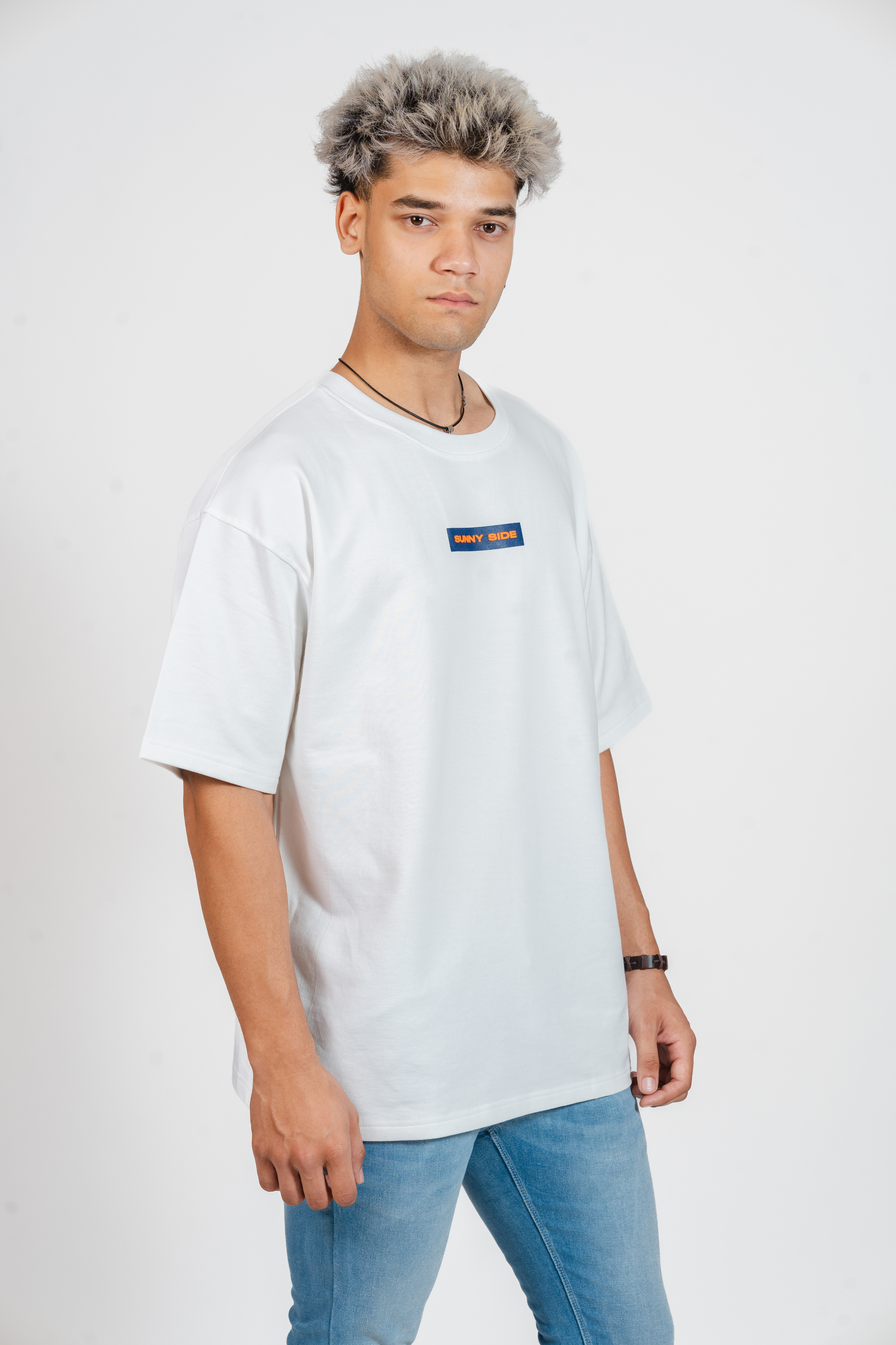 Person wearing a white t-shirt with small text that says 'Sunny Side' on a plain background